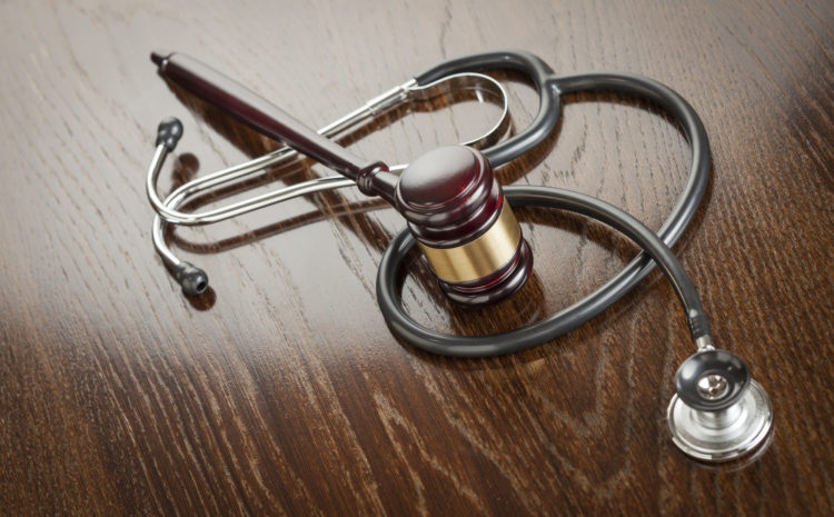 Gavel and Stethoscope on Reflective Wooden Table.